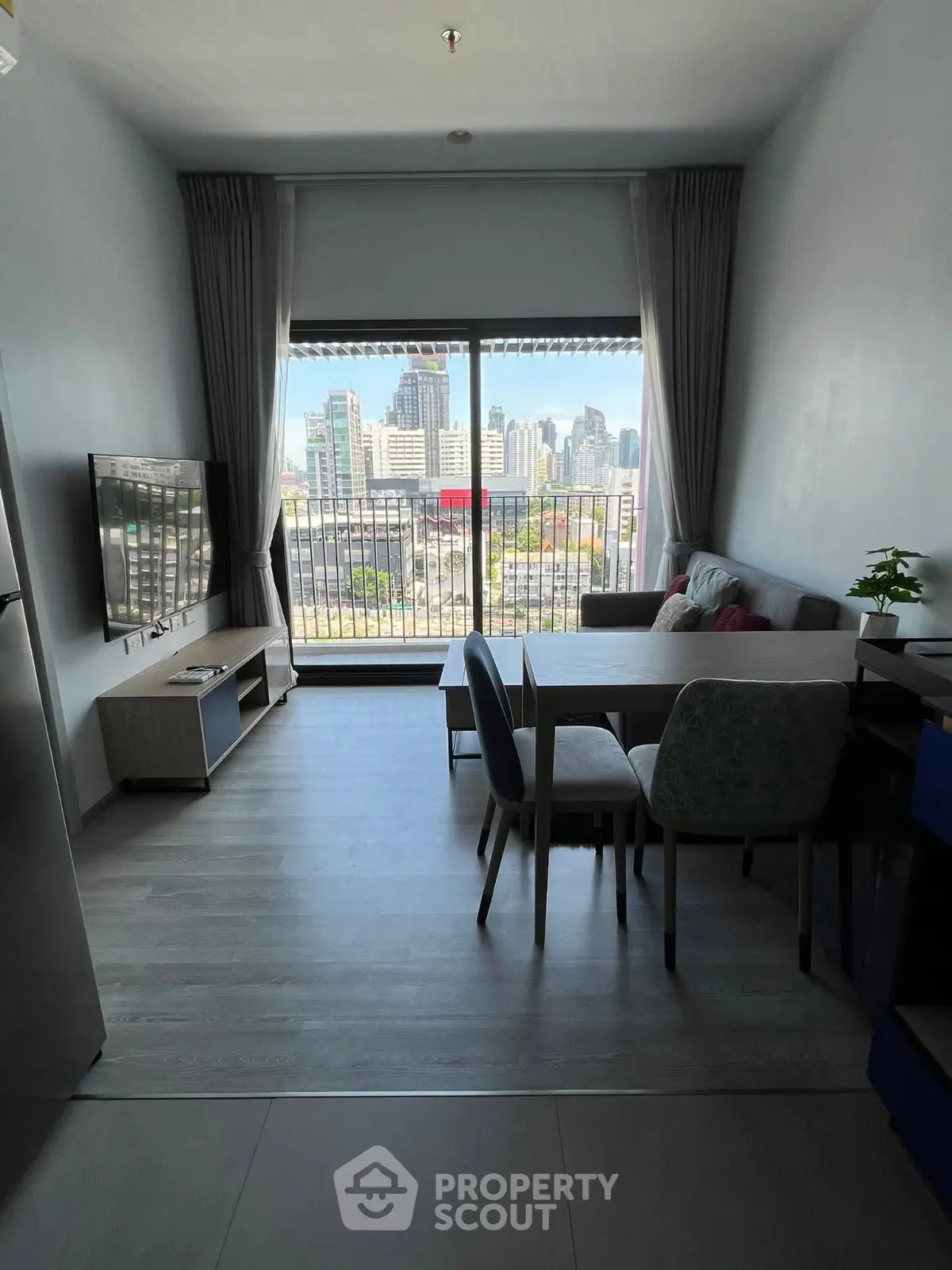 Modern living room with city view, featuring sleek furniture and large window for natural light.