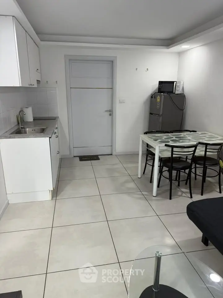 Modern kitchen with dining area featuring sleek white cabinets and contemporary furniture.