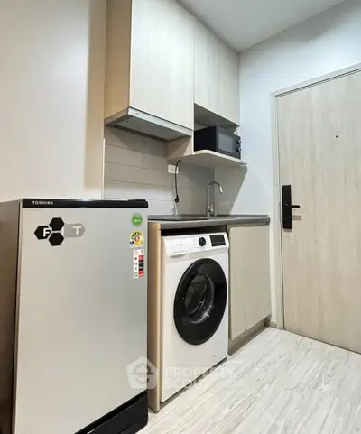 Compact kitchen with modern appliances including washing machine and fridge in a cozy apartment.