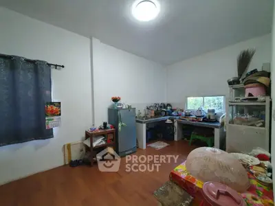 Cozy kitchen with wooden flooring and natural light, featuring a compact fridge and ample storage space.