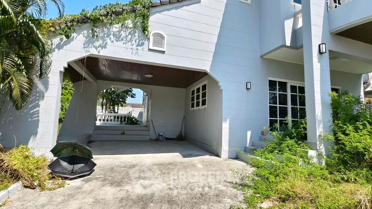 Charming house exterior with covered parking and lush greenery