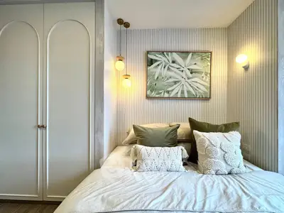 Cozy bedroom with elegant decor and soft lighting, featuring a stylish wardrobe and framed artwork.