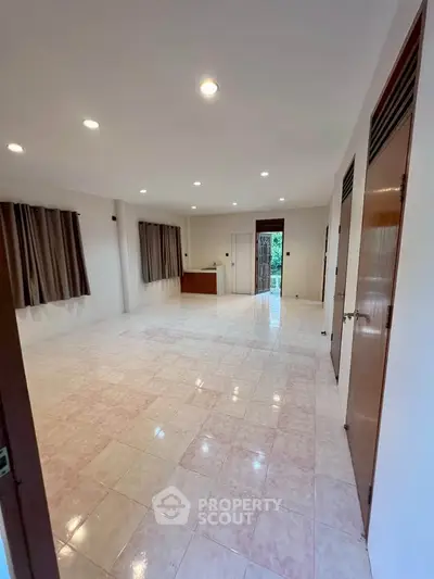 Spacious empty room with tiled flooring and natural light, ideal for customization.
