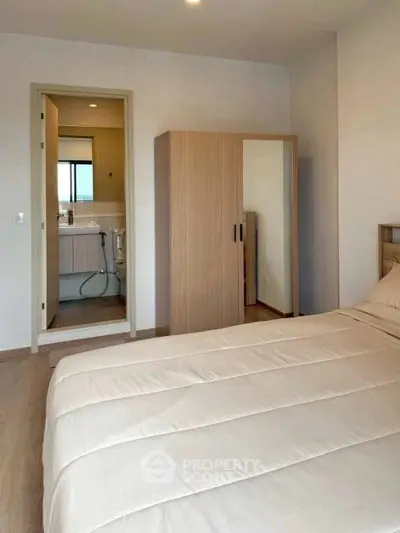 Cozy bedroom with ensuite bathroom and wooden wardrobe, perfect for modern living.