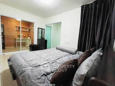 Spacious bedroom with modern decor and sliding doors leading to a cozy study area.