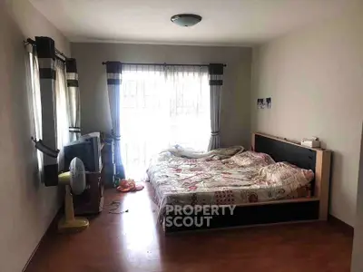 Cozy bedroom with natural light and wooden flooring, featuring a comfortable bed and modern decor.