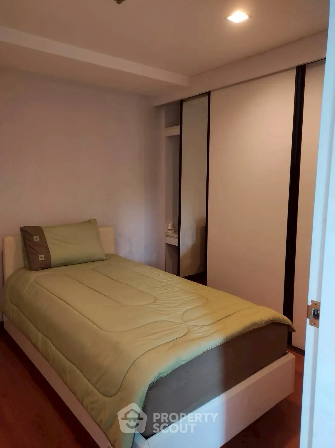Cozy bedroom with single bed and built-in wardrobe, perfect for small spaces.