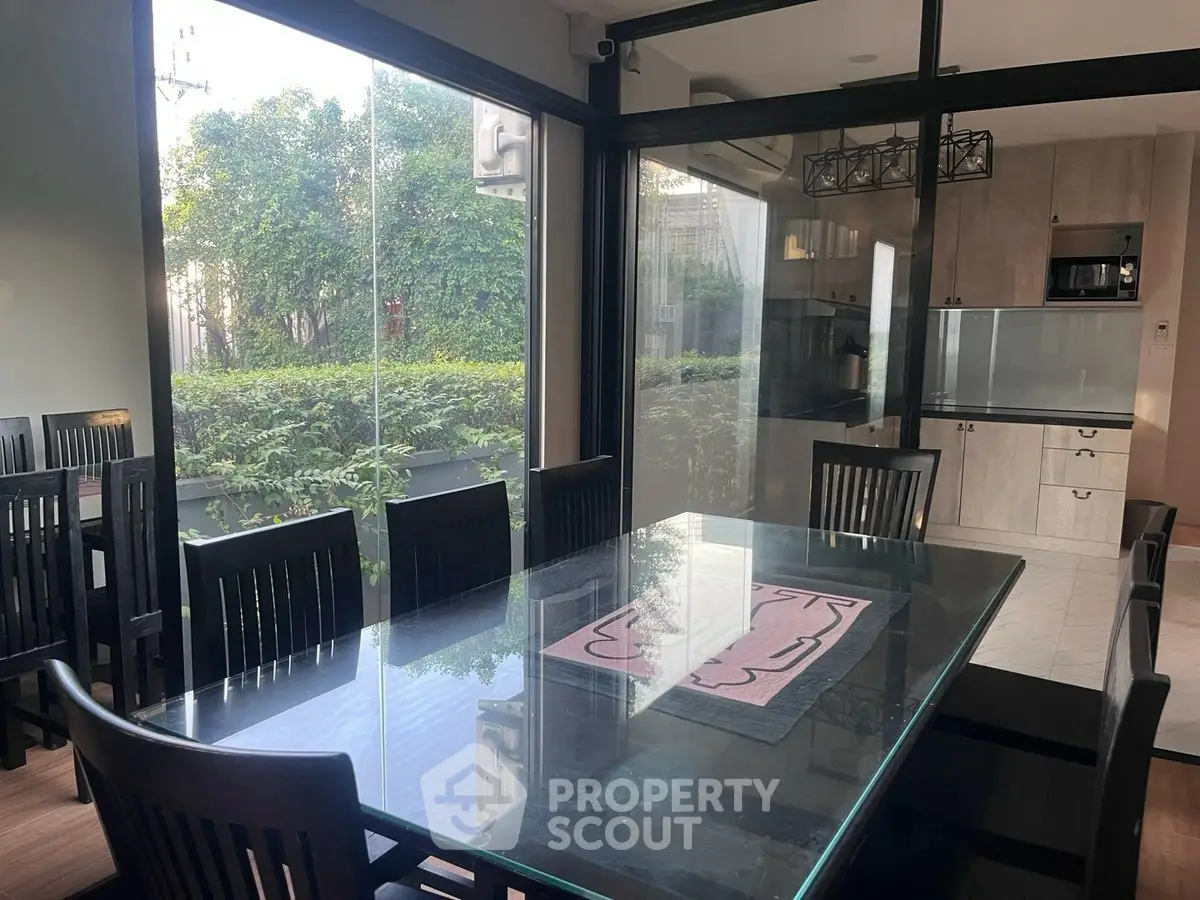 Spacious dining area with glass table and garden view in modern home