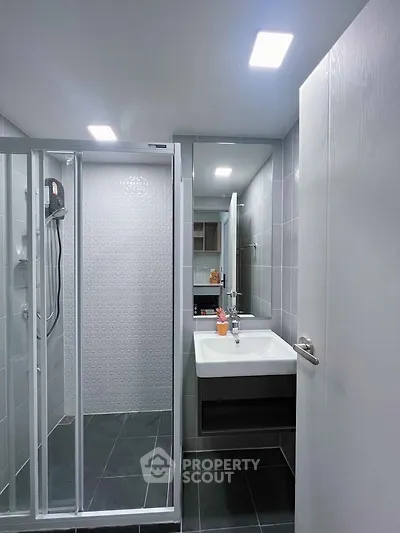 Modern bathroom with sleek shower and stylish sink in contemporary apartment.