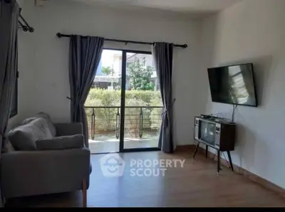 Modern living room with large window and wall-mounted TV, offering a bright and airy atmosphere.