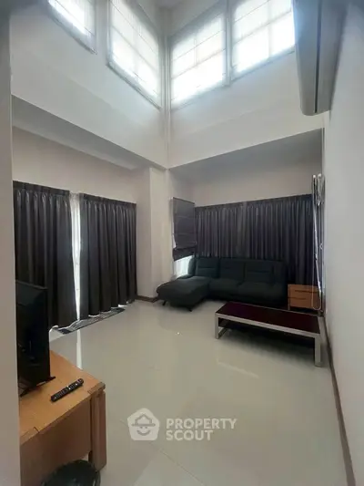 Spacious living room with high ceilings and modern furniture, perfect for relaxation and entertainment.