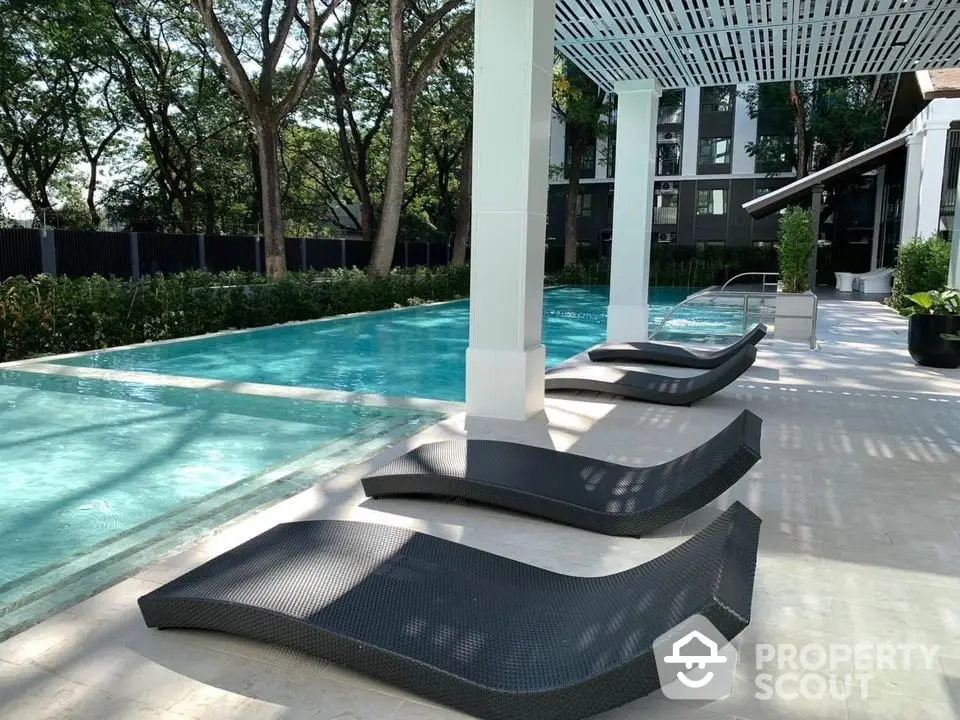 Luxurious poolside area with modern lounge chairs and lush greenery