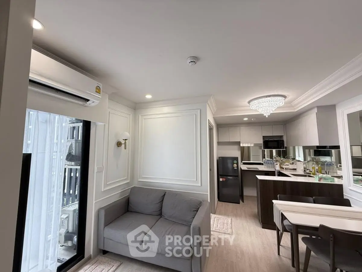 Modern open-plan living room and kitchen with elegant decor and chandelier lighting.