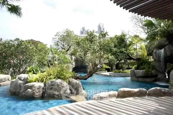Luxurious outdoor pool surrounded by lush greenery and rocks in a serene setting.