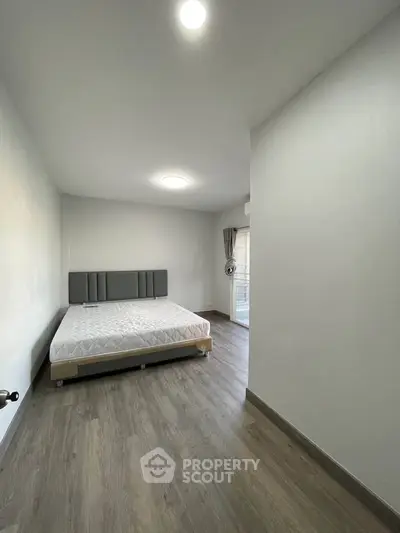 Spacious bedroom with modern flooring and natural light, featuring a comfortable bed and elegant decor.