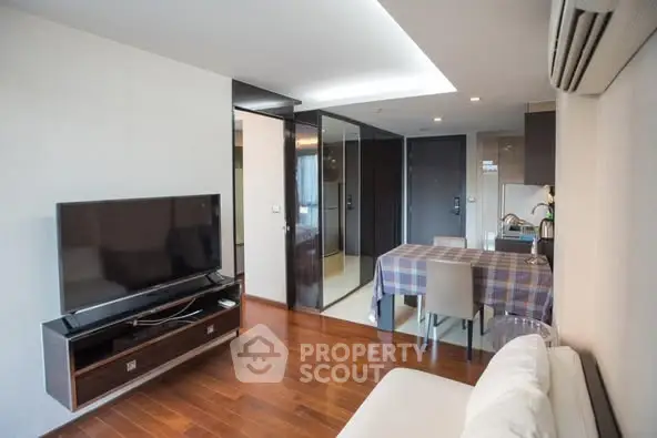 Modern living room with wooden flooring and sleek TV setup in a stylish apartment.