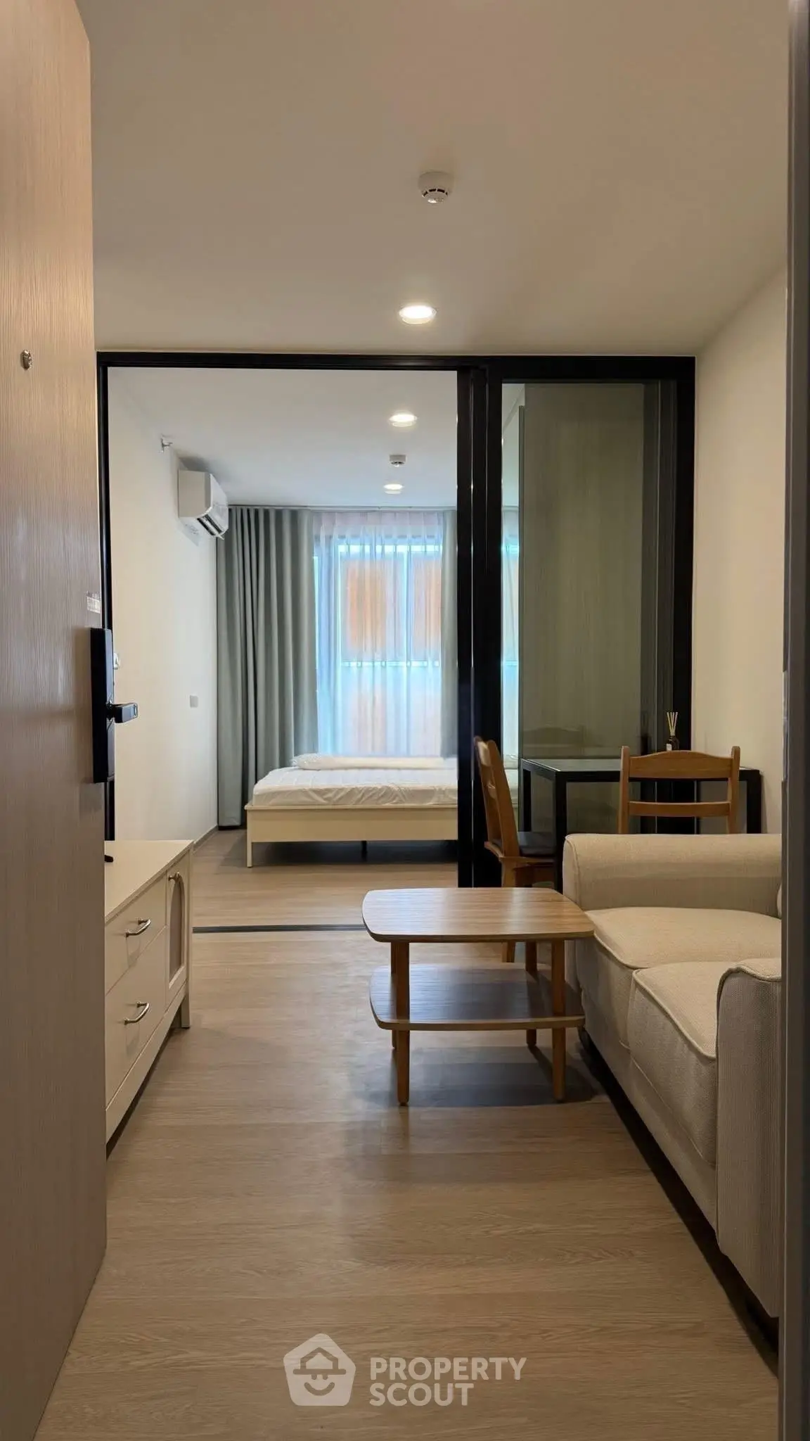 Modern apartment interior with cozy living room and bedroom, featuring sleek furniture and natural light.