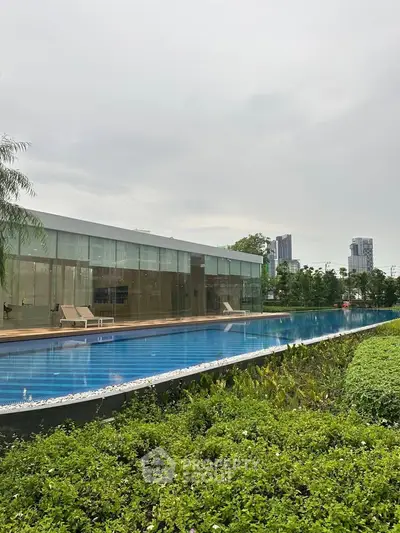 Luxurious modern building with stunning pool and lush greenery, perfect for upscale living.