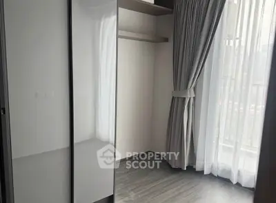 Modern empty bedroom with sleek wardrobe and large window with curtains.
