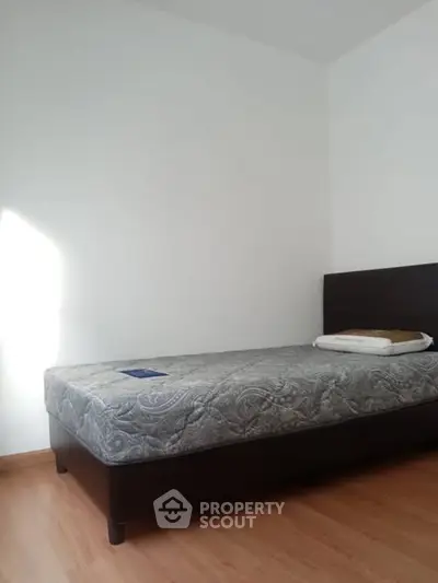 Minimalist bedroom with single bed and wooden flooring, perfect for cozy living.