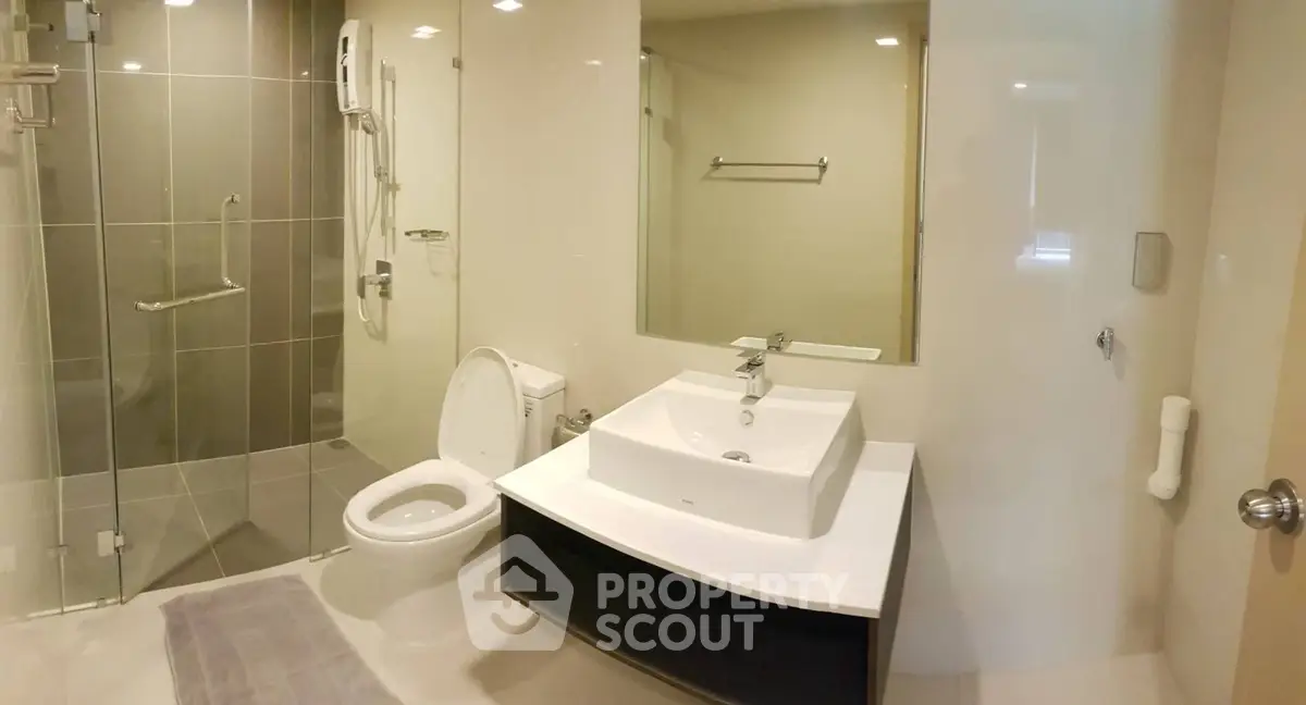 Modern bathroom with sleek fixtures and glass shower enclosure in a contemporary apartment.
