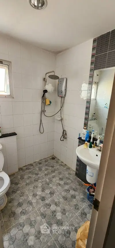 Modern bathroom with shower and sink in a tiled interior, perfect for a cozy home.