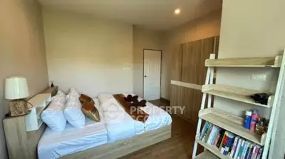 Cozy bedroom with modern wooden furniture and bookshelf, perfect for relaxation.