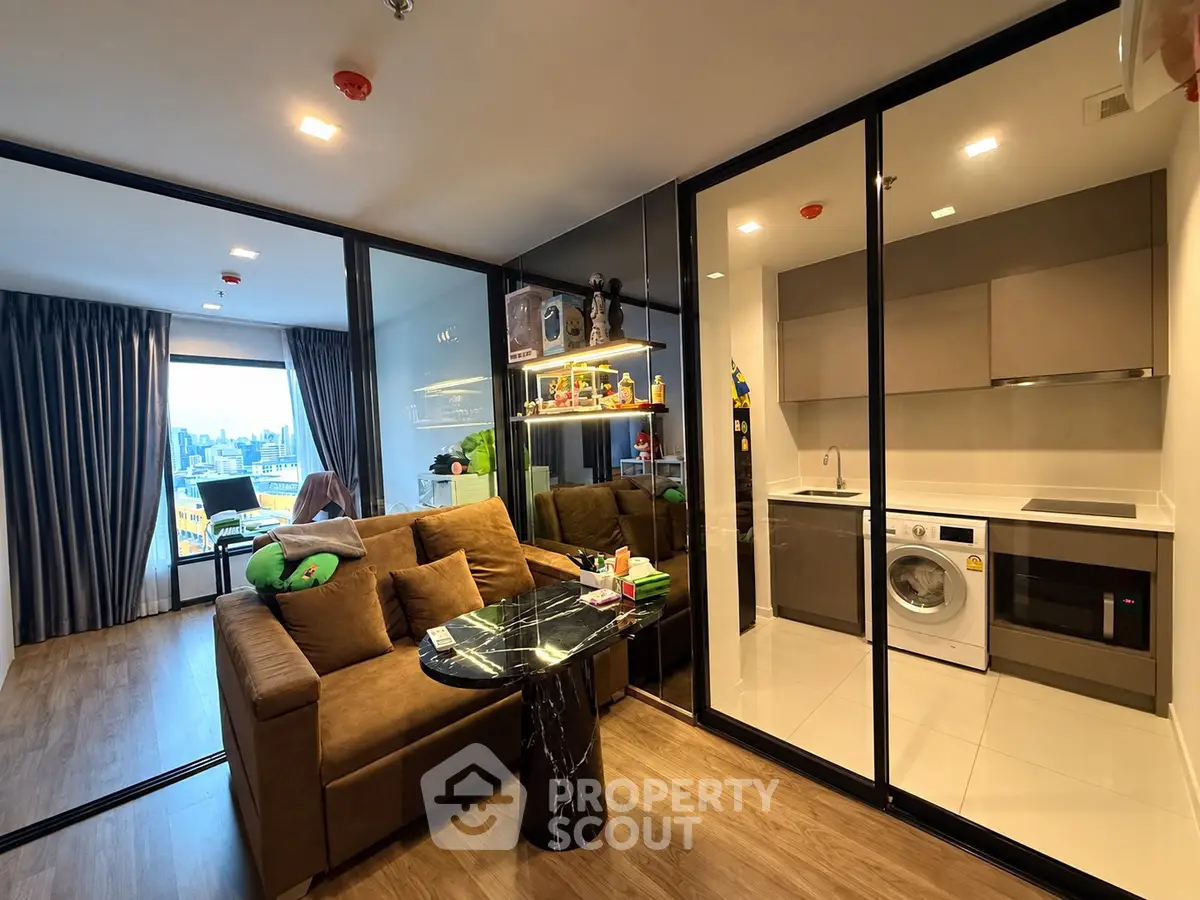 Modern open-plan living room with kitchen and city view, featuring sleek design and cozy furnishings.