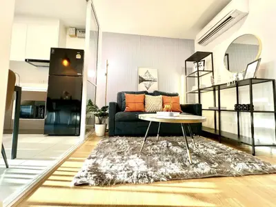 Modern living room with stylish decor and open kitchen layout, featuring cozy seating and natural light.