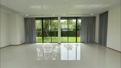 Spacious living room with large windows overlooking a lush garden, perfect for natural light lovers.