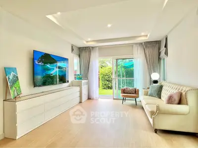 Spacious living room with elegant decor and garden view, featuring a large TV and stylish furniture.