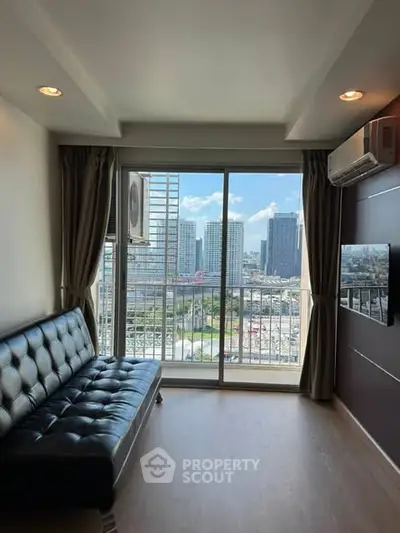 Modern living room with city view, featuring sleek black sofa and large window for natural light.