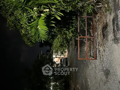 Charming night view of a secluded property entrance surrounded by lush greenery.