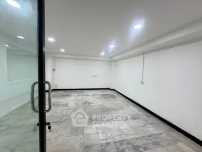 Spacious empty room with tiled flooring and glass door, ideal for office or studio setup.