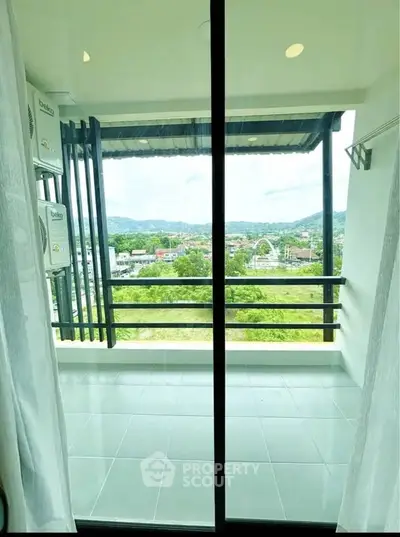 Spacious balcony with stunning panoramic view of lush greenery and distant hills, perfect for relaxation.