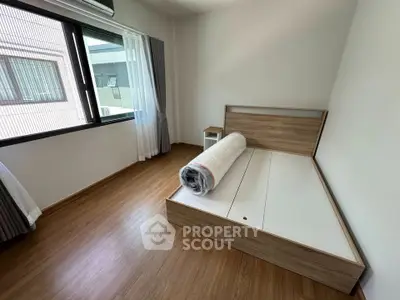 Spacious bedroom with wooden flooring and large window in modern apartment.