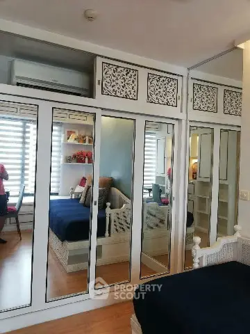 Chic bedroom with mirrored wardrobe and cozy seating area, perfect for modern living.