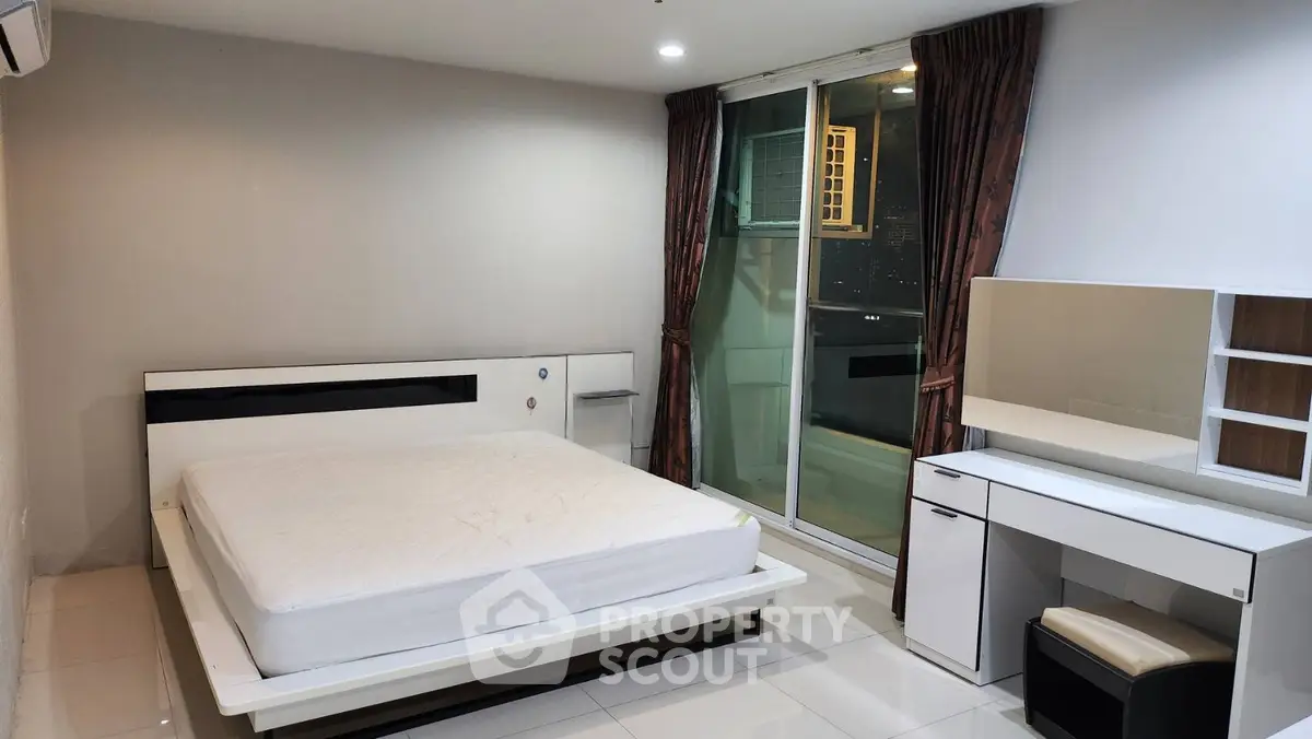 Modern bedroom with sleek furniture and city view balcony access.