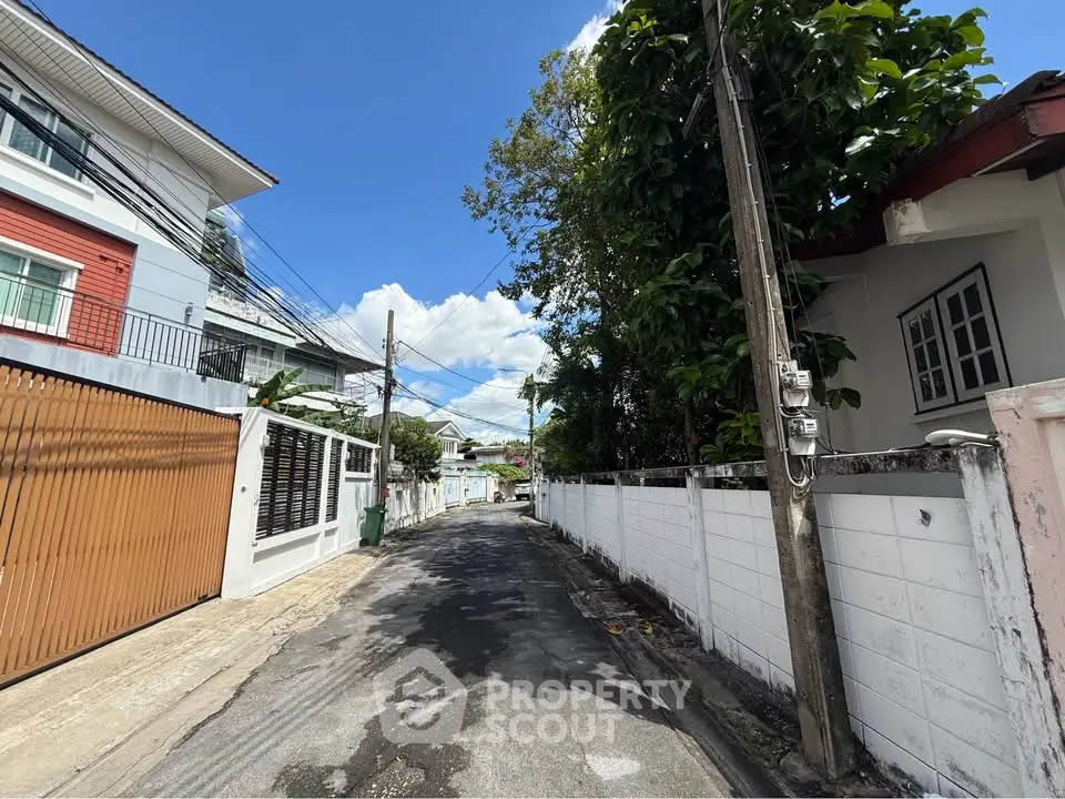 Charming residential street with modern houses and lush greenery under a clear blue sky.