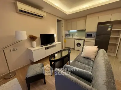 Modern living room with open kitchen, featuring washing machine and sleek appliances.