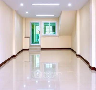 Spacious empty room with glossy tiled floors and modern lighting, ideal for customization.