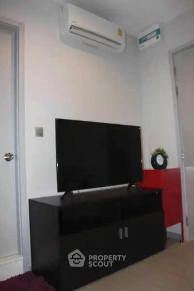 Modern living room with sleek TV setup and air conditioning unit.