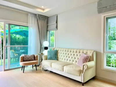 Bright and elegant living room with plush sofa and garden view, perfect for relaxation and entertaining.