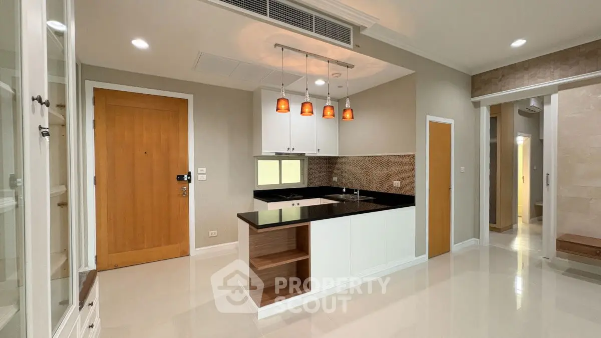Modern kitchen with sleek black countertops and pendant lighting in a stylish apartment.