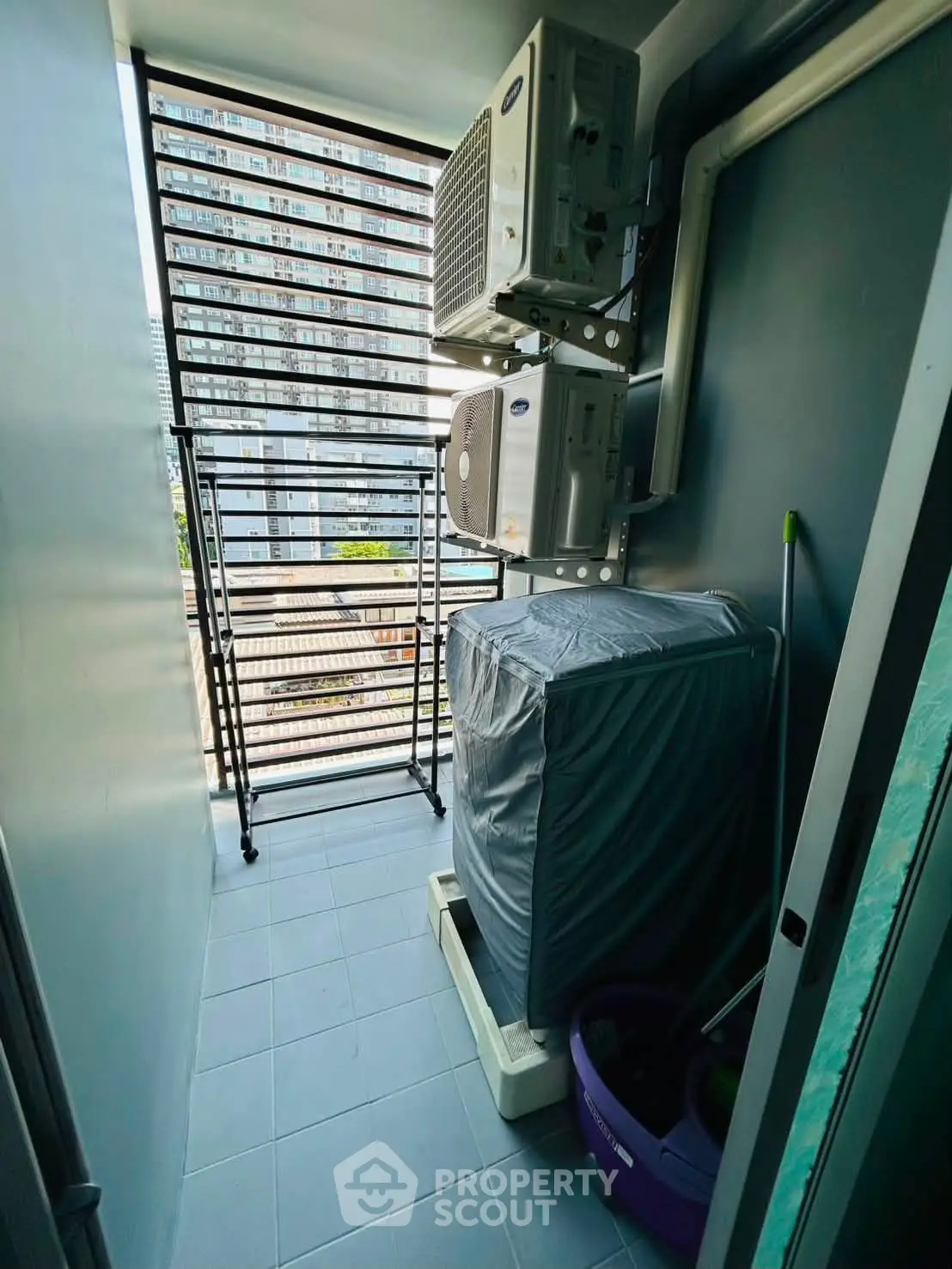 Compact balcony with air conditioning units and laundry area in modern apartment.