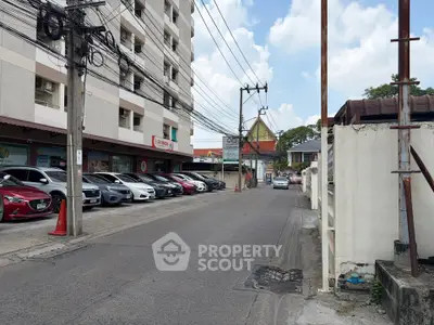 Urban street view with apartment building and parked cars, showcasing city living convenience.