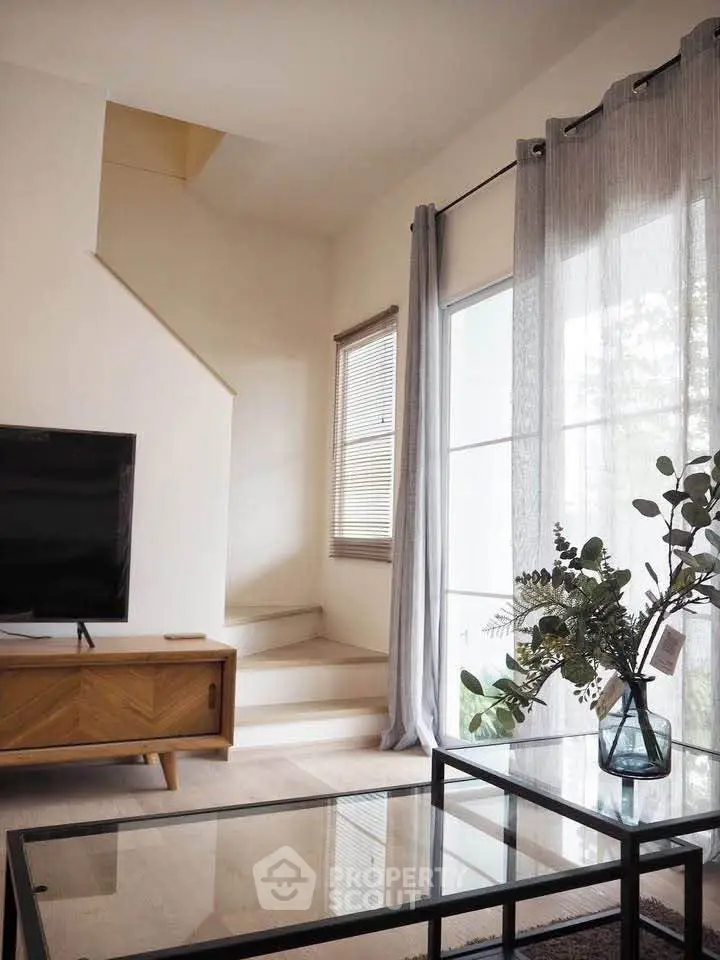Stylish living room with modern decor, large windows, and elegant staircase, perfect for contemporary living.