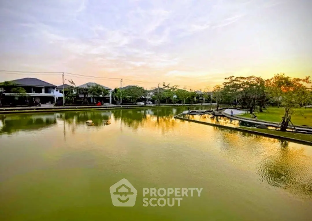 Scenic view of serene lake with modern homes and lush greenery at sunset, perfect for tranquil living.