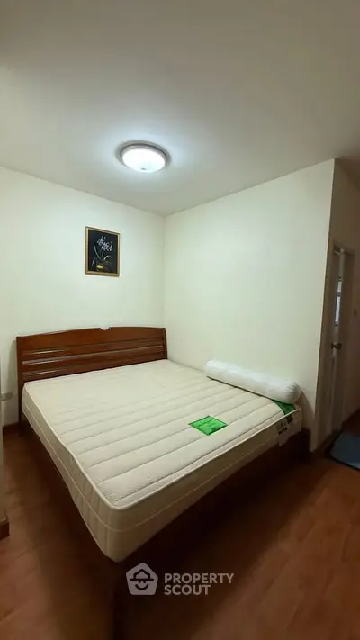Cozy bedroom with wooden flooring and a comfortable bed, perfect for relaxation.