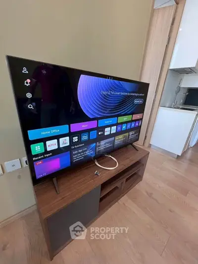Modern living room with sleek TV and stylish wooden stand in a cozy apartment setting.